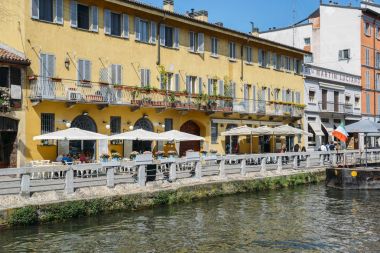 İnsanlar, Milano'nun popüler Navigli bölgesinde bir restoranın terasında dinlenin