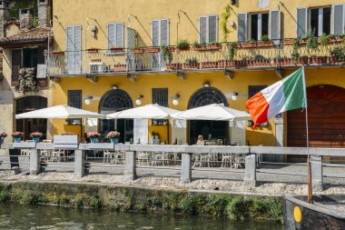 İnsanlar, Milano'nun popüler Navigli bölgesinde bir restoranın terasında dinlenin