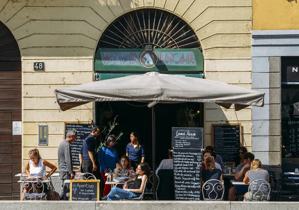 People relax at a restaurant terrace in the popular Navigli district of Milan — Stock Photo, Image