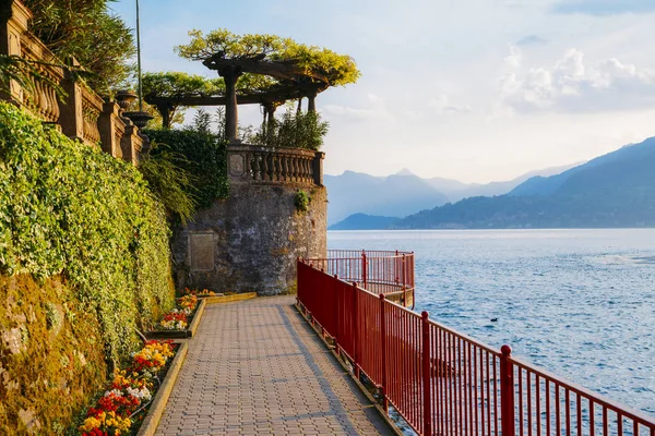Arco jardim vermelho no litoral que leva para a bela e histórica cidade de Varenna, na borda do Lago de Como, no norte da região italiana da Lombardia . — Fotografia de Stock