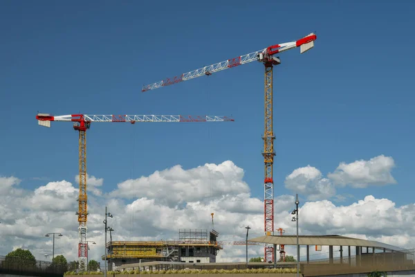 Bouwkranen en niet-identificeerbare bouwvakarbeiders op een bouwterrein met blauwe lucht en kopieerruimte. — Stockfoto