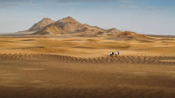 Group of four hikers in the Dasht-e-Lut, a large salt desert located in the provinces of Kerman, Sistan and Baluchestan, Iran. — Stock Photo, Image