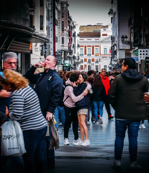 Dos jóvenes se abrazan entre sí en medio del caos de una concurrida calle comercial en Madrid, España — Foto de Stock