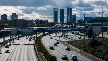 Heavy commuter highway traffic on the A1 highway in Las Tablas looking towards the Cuatro Torres Business district in downtown Madrid clipart