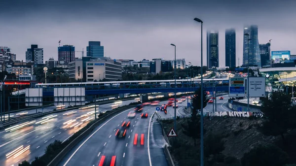 Lång exponering av tung pendeltrafik mot Cuatro Torres Business District i Madrid, Spanien. — Stockfoto