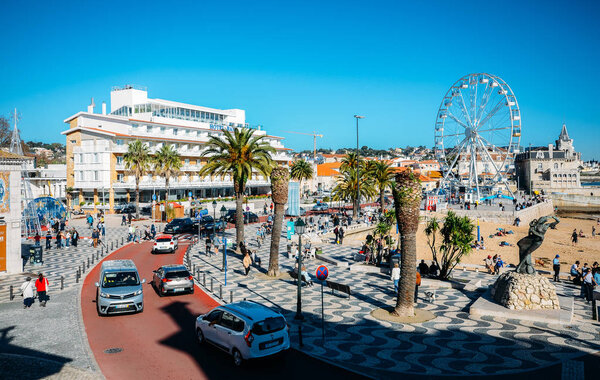 Crowded sandy beach in Cascais near Lisbon, Portugal during the winter with Christmas ferris-wheel