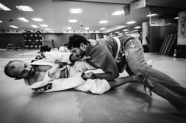 Twee jonge mannen oefenen Braziliaanse Jiu-Jitsu sparring, een soort vechtsport met een kimono gi - geen geënsceneerde inhoud of tijdens een besloten evenement — Stockfoto