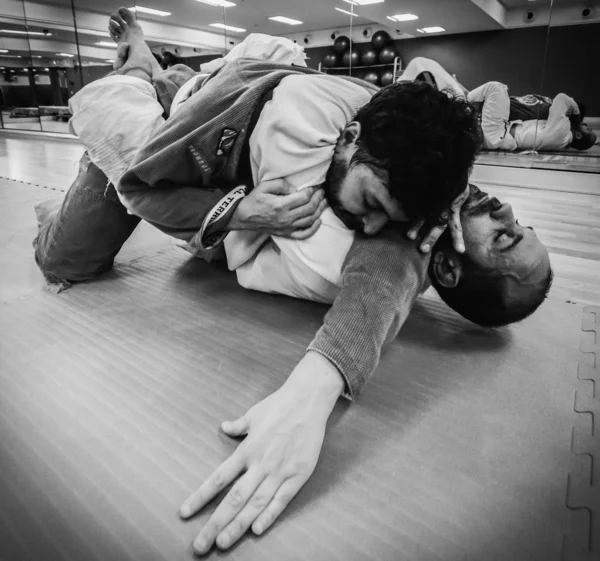 Two young men practice Brazilian Jiu-Jitsu sparring, a grappling type martial arts with a kimono gi - NOT STAGED CONTENT OR AT CLOSED EVENT — Stock Photo, Image