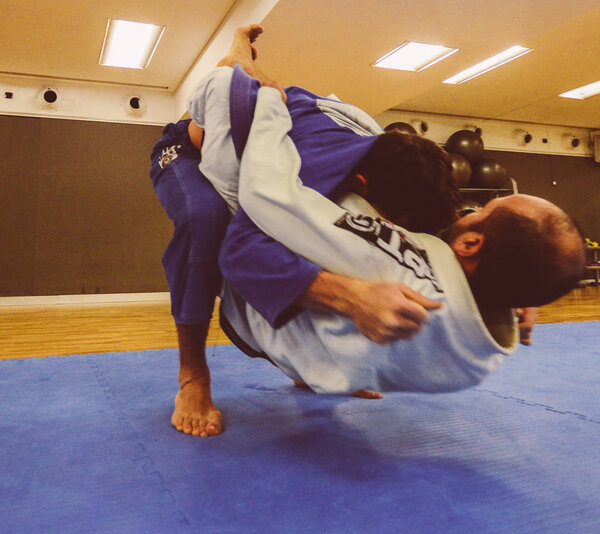 Two young men practice Brazilian Jiu-Jitsu sparring, a grappling type martial arts with a kimono gi - NOT STAGED CONTENT OR AT CLOSED EVENT