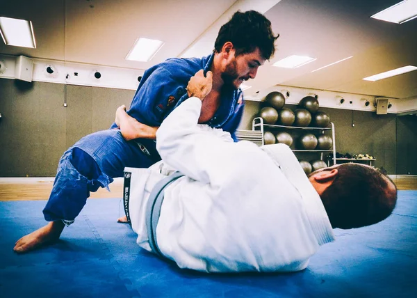 İki genç adam Brezilya Jiu-Jitsu idmanı yapıyor, bir kimono giyle yakalama sanatı - Sahnelenmemiş İçerik veya Kapalı Etkinlik