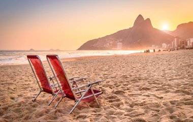 Beach deck chair against a backdrop of Two Brothers Mountain in Rio de Janeiro, Brazil clipart