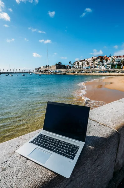 Generic notebook laptop on sunny deserted sandy beach backround. Paradise home-office concept especially during Coronavirus Covid-19 outbreak