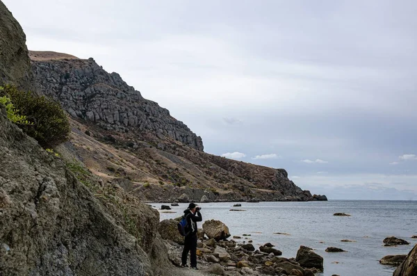 旅游和旅行 带着蓝色背包的人 海滨的海景 高山和石头 — 图库照片