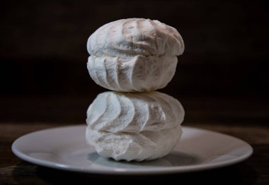 Beyaz şekerlemeler, bir piramide katlanmış pasta, teke tek, tahta bir masada beyaz bir tabakta..