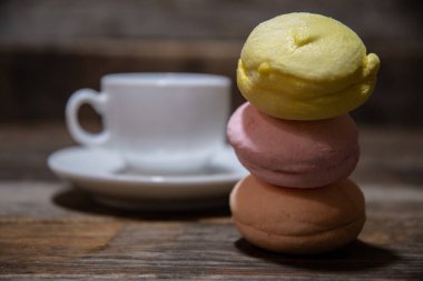Ahşap bir masada beyaz bir kahve fincanının arka planında üç lezzetli, çok renkli pasta makaronu..