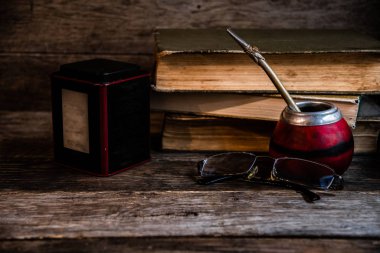 Eski kitaplar, bardaklar, kabak, bombilla eski ahşap tahtaların arka planında, derin ve keyifli okuma koşulları.