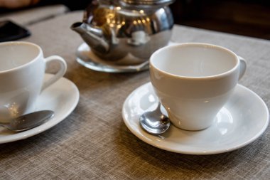 Çay demlemek için metal bir çaydanlık, beyaz bir seramik bardak, kafedeki masada duran şeker için cam bir vazo..