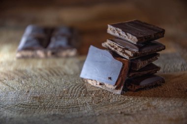 Black chocolate with truffle filling on a kitchen wooden board.