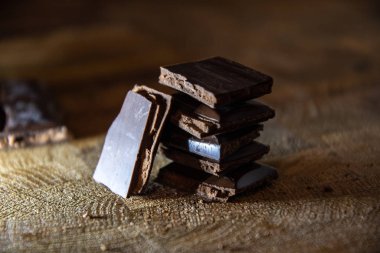 Black chocolate with truffle filling on a kitchen wooden board.
