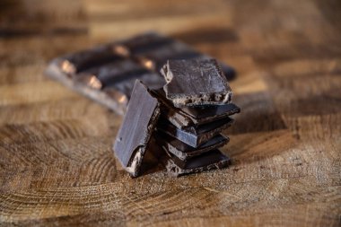 Black chocolate with truffle filling on a kitchen wooden board.
