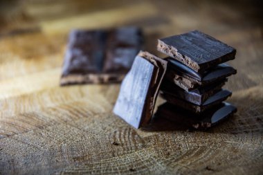 Black chocolate with truffle filling on a kitchen wooden board.