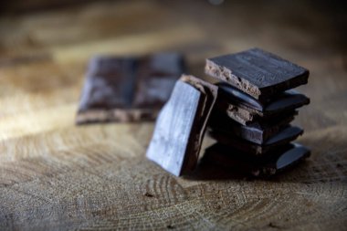 Black chocolate with truffle filling on a kitchen wooden board.