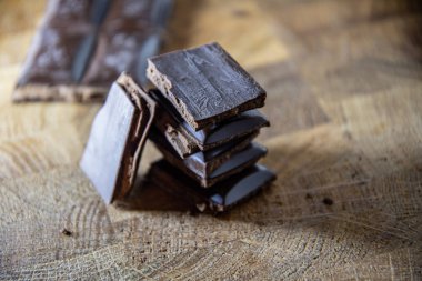 Black chocolate with truffle filling on a kitchen wooden board.