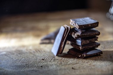 Black chocolate with truffle filling on a kitchen wooden board.