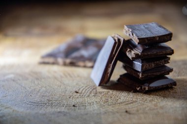 Black chocolate with truffle filling on a kitchen wooden board.