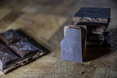 Black chocolate with truffle filling on a kitchen wooden board.
