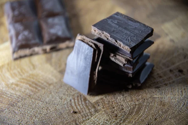 Black chocolate with truffle filling on a kitchen wooden board.