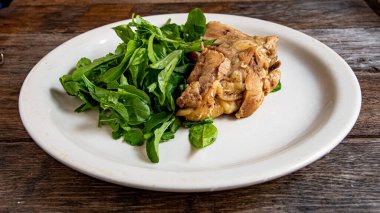 Ev yemeği. Arugula ve mutfak masasında beyaz bir tabakta et..