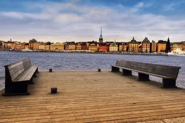 Bänkar på bakgrunden av den gamla vackra staden på vattnet — Stockfoto