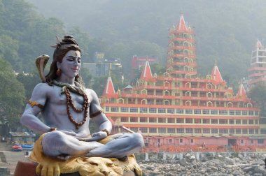 Rishikesh, Hindistan - Kasım, 3, 2017. Ganga Rishikesh, Tera Manzil Tapınağı, Trayambakeshwar arka planda içinde nehir üzerinde meditasyon oturan Shiva heykeli