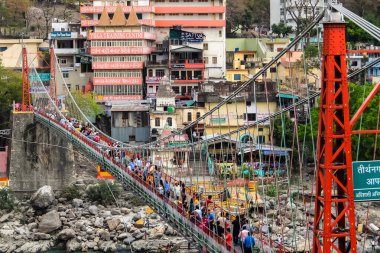 Rishikesh, Hindistan - Nisan 2018. Rishikesh 'teki Ganga nehir setinin güzel manzarası. İnsanlar Laxman Jhula köprüsünü geçiyor..
