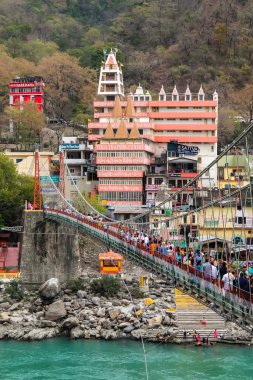 Rishikesh, Hindistan - Nisan 2018. Rishikesh 'teki Ganga nehir setinin güzel manzarası. İnsanlar Laxman Jhula köprüsünü geçiyor..