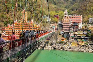 Rishikesh, Hindistan - Mart 2018. Rishikesh 'teki Ganga nehir setinin güzel manzarası. İnsanlar Laxman Jhula köprüsünü geçiyor..