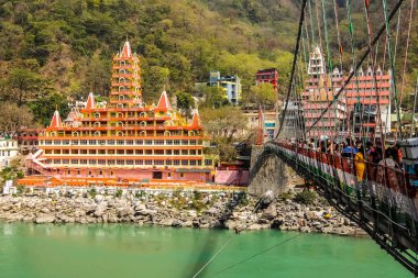 Rishikesh, Hindistan - Mart 2018. Rishikesh 'teki Ganga nehir setinin güzel manzarası. İnsanlar Laxman Jhula köprüsünü geçiyor..
