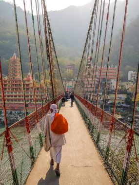 Rishikesh, Hindistan - Mart 2018. Rishikesh 'teki Ganga nehir setinin güzel manzarası. İnsanlar Laxman Jhula köprüsünü geçiyor..