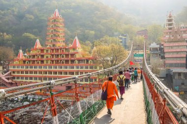 Rishikesh, Hindistan - Mart 2018. Rishikesh 'teki Ganga nehir setinin güzel manzarası. İnsanlar Laxman Jhula köprüsünü geçiyor..