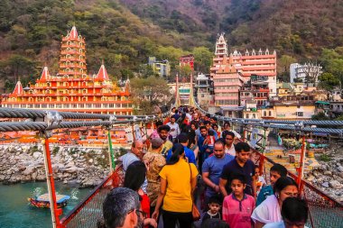 Rishikesh, Hindistan - Mart 2018. Rishikesh 'teki Ganga nehir setinin güzel manzarası. İnsanlar Laxman Jhula köprüsünü geçiyor..