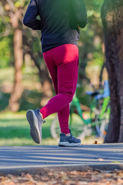 A man and a  woman are jogging in the evening on the public park