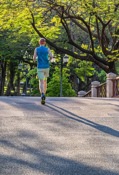 A man and a  woman are jogging in the evening on the public park