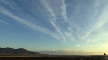 Hızla geçen bulutlar, tepenin altındaki şehir.