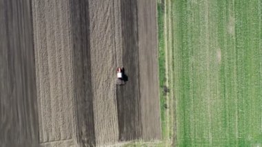 Tepeden tırnağa. Traktör, toprağı ekime hazırlıyor. Hava görüntüsü. Traktördeki çiftçi tarlalarda arazi hazırlıyor. Traktör tarlayı sürüyor. Tarım endüstrisi