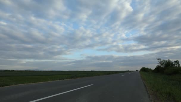 TIME LAPSE - une route asphaltée vide entre les champs au crépuscule 