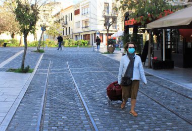 Atina, Yunanistan, 14 Mart 2020 - Koronavirüs salgını nedeniyle yüzünde maskeyle Atina sokaklarında yürüyen kadın.