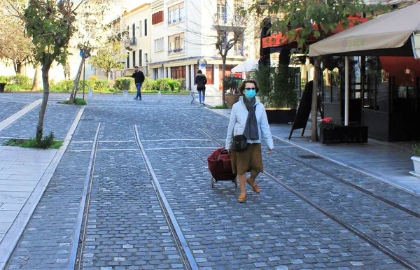 Atina, Yunanistan, 14 Mart 2020 - Koronavirüs salgını nedeniyle yüzünde maskeyle Atina sokaklarında yürüyen kadın.