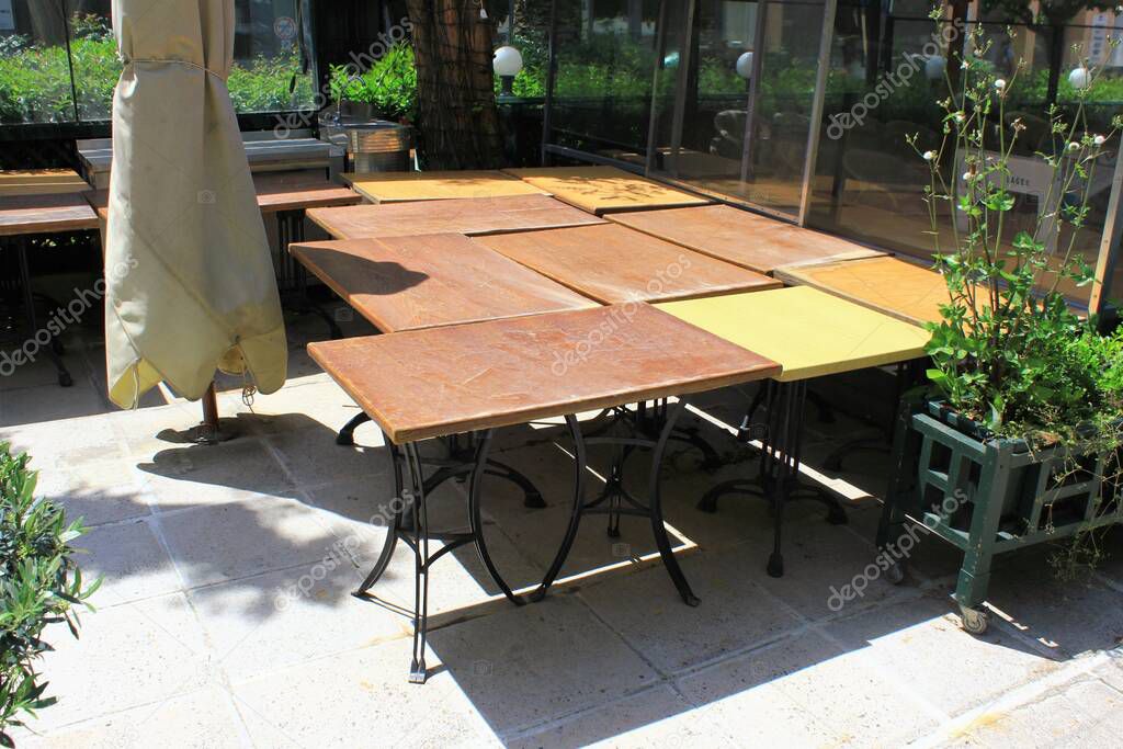 Athens, Greece, May 6 2020 - Tables and chairs stacked outside closed cafe-restaurant during the Coronavirus lockdown.