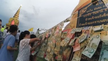 Kimliği belirsiz kişi teklif para altın stupa çevresinde iş parçacığında asmak 